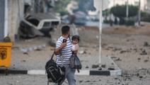 فلسطيني يحمل ابنته وبعض حاجيّاته وهاتفه في غزة (علي جاد الله/الأناضول)