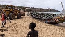 سحب قارب صيد استخدم في رحلة هجرة في السنغال (جون ويسيلز/ فرانس برس)