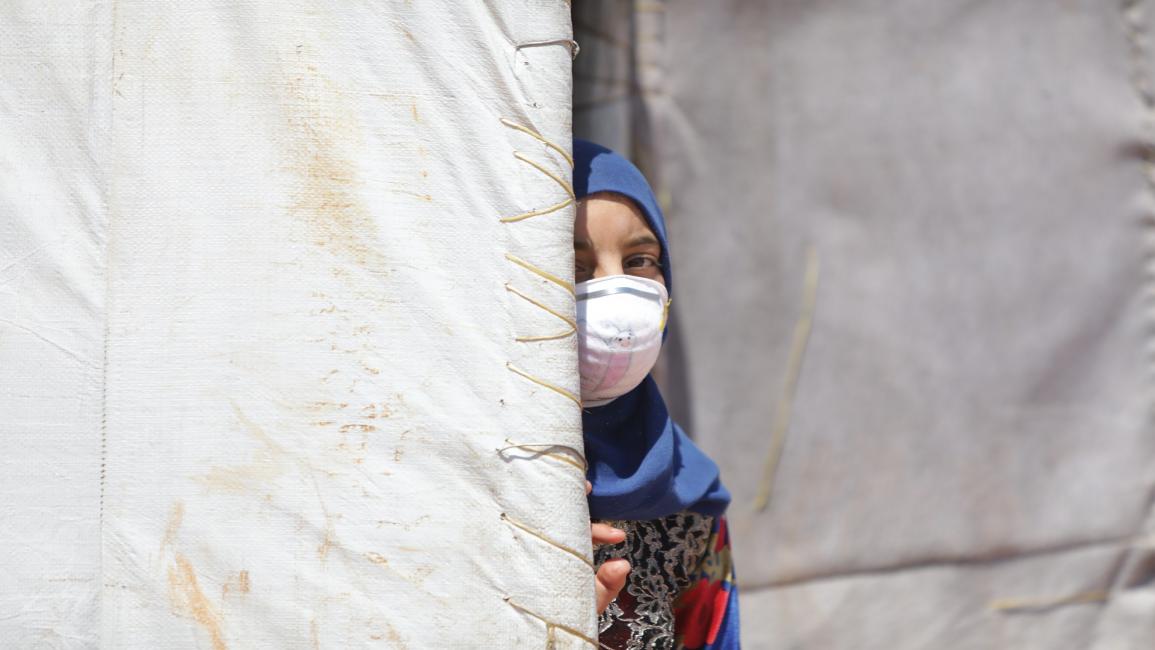 Daily life in refugee camps in Idlib IDLIB, SYRIA - JUNE 19: A Syrian girl wearing a medical mask as a precaution against coronavirus (Covid-19) pandemic is seen at a refugee camp where thousands of displaced Syrians shelter due to Assad Regime forces and its allies ongoing attacks over residential areas, in Idlib, Syria on June 19, 2020. Displaced civilians have difficulties in reaching many basic living needs such as food, shelter, education and health in camps. (Photo by Bekir Kasim/Anadolu Agency via Ge