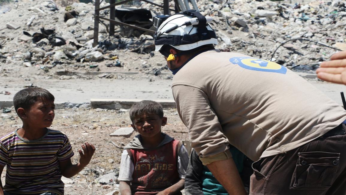 الدفاع المدني مع أطفال قصفت مدرستهم بإدلب(إبراهيم أبو ليث/الأناضول)