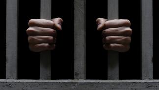 صورة تعبيرية تبيّن قضبان زنزانة سجن وسجيناً (Getty)