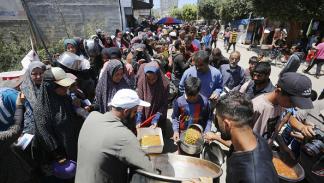 فلسطينيون نازحون في دير البلح في طوابير للحصول على الطعام، 13 مايو2024 (أشرف عمرة/الأناضول)