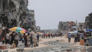 فلسطينيون يتسوقون بين الدمار في خانيونس، في 28 مايو 2024 (الأناضول)