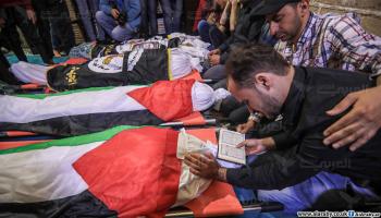 شاب فلسطيني يتلو آيات من القرآن أمام جثامين الشهداء (العربي الجديد)